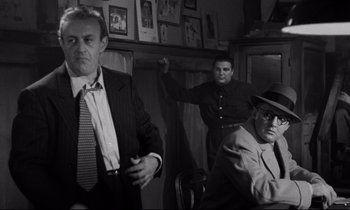 Movie still from “On the Waterfront” (1954), directed by Elia Kazan – A group of men standing next to each other in a room; Medium shot, Low angle