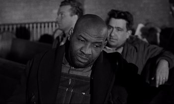 Movie still from “On the Waterfront” (1954), directed by Elia Kazan – A black and white photo of a man in a crowd; Medium shot, Low angle