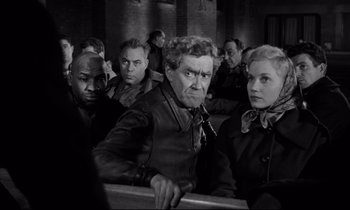 Movie still from “On the Waterfront” (1954), directed by Elia Kazan – A group of men and women sitting next to each other; Medium shot, Over the shoulder angle