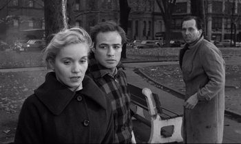 Movie still from “On the Waterfront” (1954), directed by Elia Kazan – A black - and - white photo of a man and a woman and another man; Medium shot, Over the shoulder angle