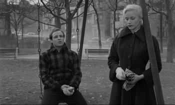 Movie still from “On the Waterfront” (1954), directed by Elia Kazan – A man and a woman sitting on a swing; Medium shot, High angle