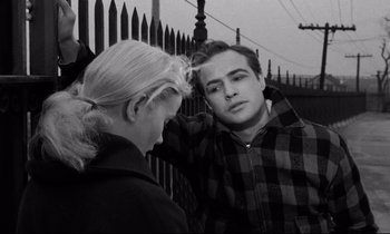 Movie still from “On the Waterfront” (1954), directed by Elia Kazan – A man and a woman standing next to each other near a fence; Medium shot, Over the shoulder angle