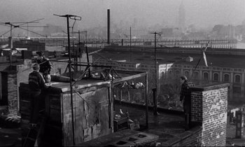 Movie still from “On the Waterfront” (1954), directed by Elia Kazan – A black and white photo of a man standing on top of a building; Wide shot, High angle