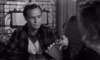 Movie still from “On the Waterfront” (1954), directed by Elia Kazan – A man holding a glass of beer in his hand; Close Up shot, Over the shoulder angle