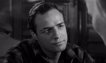 Movie still from “On the Waterfront” (1954), directed by Elia Kazan – Black and white photograph of a man looking at the camera; Close Up shot, Over the shoulder angle