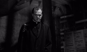 Movie still from “On the Waterfront” (1954), directed by Elia Kazan – A black and white photo of a man in a priest's outfit; Medium shot, Low angle