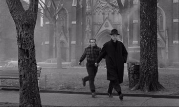 Movie still from “On the Waterfront” (1954), directed by Elia Kazan – Two men walking down the street in front of a church; Wide shot, Over the shoulder angle