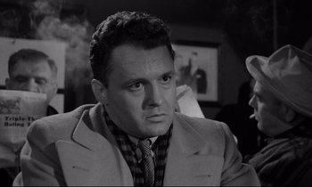 Movie still from “On the Waterfront” (1954), directed by Elia Kazan – A man wearing a suit and tie in black and white; Close Up shot, Low angle