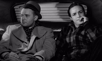 Movie still from “On the Waterfront” (1954), directed by Elia Kazan – A man and a woman sitting next to each other in the back of a car; Medium shot, Low angle