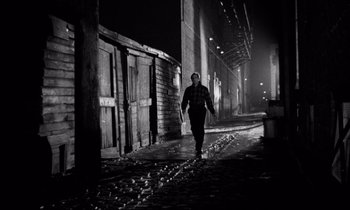 Movie still from “On the Waterfront” (1954), directed by Elia Kazan – A man walking down a street at night; Wide shot, High angle