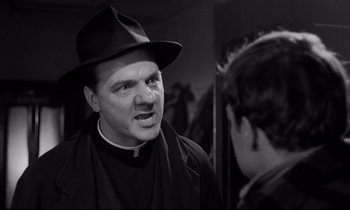 Movie still from “On the Waterfront” (1954), directed by Elia Kazan – A man wearing a hat and a priest's outfit talking to another man; Close Up shot, Over the shoulder angle