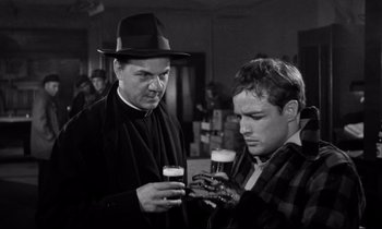 Movie still from “On the Waterfront” (1954), directed by Elia Kazan – Two men are drinking beer together in a room; Medium shot, Low angle
