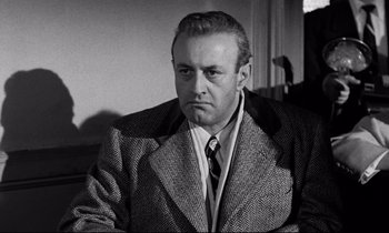 Movie still from “On the Waterfront” (1954), directed by Elia Kazan – An older man wearing a suit and tie; Close Up shot, Low angle