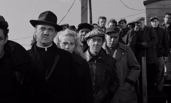 Movie still from “On the Waterfront” (1954), directed by Elia Kazan – A group of people standing in front of a power pole; Medium shot, Low angle