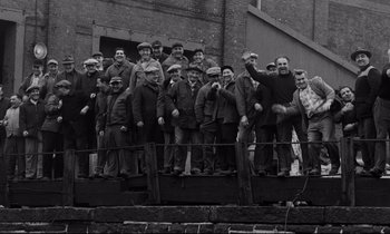 Movie still from “On the Waterfront” (1954), directed by Elia Kazan – A group of men standing next to each other on a rail; Wide shot, High angle