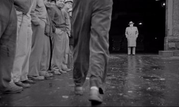 Movie still from “On the Waterfront” (1954), directed by Elia Kazan – A group of men standing in front of a man in a suit; Wide shot, Low angle