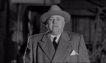 Movie still from “On the Waterfront” (1954), directed by Elia Kazan – An older man wearing a suit and a hat; Close Up shot, Low angle