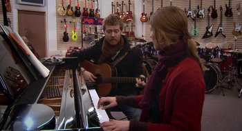 Movie still from “Once” (2007), directed by John Carney – A man and a woman playing guitar and a piano; Medium shot, Over the shoulder angle