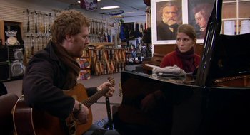 Movie still from “Once” (2007), directed by John Carney – A man and a woman playing a guitar in a music store; Medium shot, Over the shoulder angle