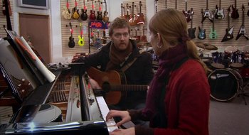 Movie still from “Once” (2007), directed by John Carney – A man and a woman are playing a guitar and a piano; Medium shot, Over the shoulder angle