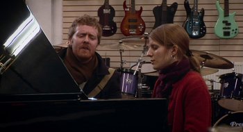Movie still from “Once” (2007), directed by John Carney – A man and a woman in a music store; Medium shot, High angle