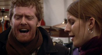 Movie still from “Once” (2007), directed by John Carney – A man and a woman are laughing together; Close Up shot, Over the shoulder angle