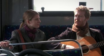 Movie still from “Once” (2007), directed by John Carney – A man and a woman are sitting on a bus; Medium shot, Over the shoulder angle