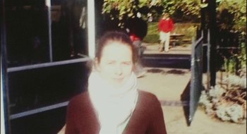 Movie still from “Once” (2007), directed by John Carney – A woman wearing a scarf standing in front of a bench; Medium shot, High angle