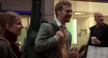 Movie still from “Once” (2007), directed by John Carney – A man in a suit and tie holding onto a guitar case; Medium shot, Over the shoulder angle