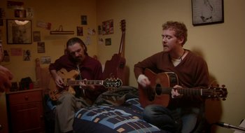 Movie still from “Once” (2007), directed by John Carney – A couple of men sitting on top of a bed playing guitars; Medium shot, High angle