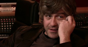 Movie still from “Once” (2007), directed by John Carney – A person sitting in a chair holding his hand to his face; Close Up shot, High angle