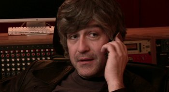 Movie still from “Once” (2007), directed by John Carney – A man in a brown shirt talking on a cell phone; Close Up shot, High angle