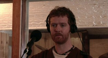 Movie still from “Once” (2007), directed by John Carney – A man with a beard wearing headphones and a microphone; Close Up shot, Low angle