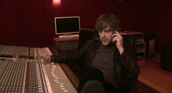 Movie still from “Once” (2007), directed by John Carney – A man sitting in front of a sound board talking on a cell phone; Medium shot, Low angle