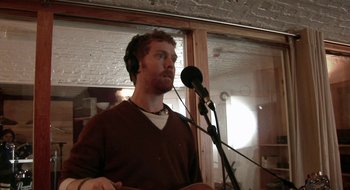 Movie still from “Once” (2007), directed by John Carney – A man with a microphone and headphones in a room; Close Up shot, Low angle