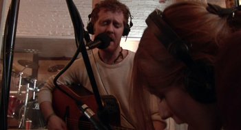Movie still from “Once” (2007), directed by John Carney – A man and a woman are singing into a microphone; Medium shot, High angle