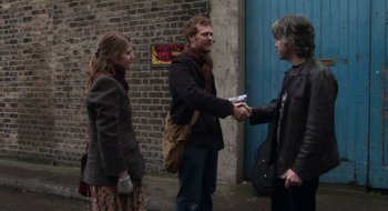 Movie still from “Once” (2007), directed by John Carney – Two women and a man shaking hands in front of a brick wall; Medium shot, Over the shoulder angle