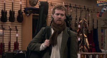 Movie still from “Once” (2007), directed by John Carney – A man with a beard wearing a jacket and a scarf; Medium shot, Over the shoulder angle