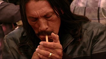Movie still from “Once Upon a Time in Mexico” (2003), directed by Robert Rodriguez – A man with long black hair is smoking a cigarette; Close Up shot, Low angle