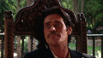 Movie still from “Once Upon a Time in Mexico” (2003), directed by Robert Rodriguez – A person sitting in a chair wearing a suit; Close Up shot, Low angle