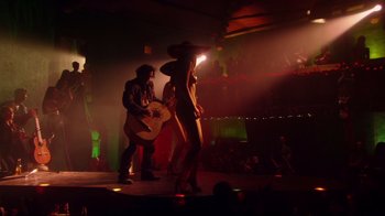 Movie still from “Once Upon a Time in Mexico” (2003), directed by Robert Rodriguez – A group of people standing on a stage with a guitar; Wide shot, Low angle