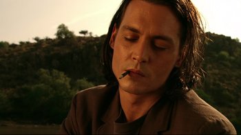 Movie still from “Once Upon a Time in Mexico” (2003), directed by Robert Rodriguez – A man with long hair is smoking a cigarette; Close Up shot, Low angle