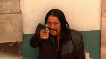 Movie still from “Once Upon a Time in Mexico” (2003), directed by Robert Rodriguez – A man with long hair holding a gun pointed at the camera; Close Up shot, Low angle
