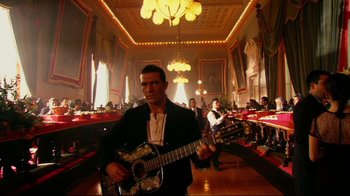 Movie still from “Once Upon a Time in Mexico” (2003), directed by Robert Rodriguez – A man holding a guitar while standing in a room; Wide shot, Low angle