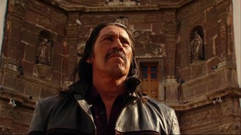 Movie still from “Once Upon a Time in Mexico” (2003), directed by Robert Rodriguez – A man with long black hair wearing a leather jacket; Medium shot, Low angle