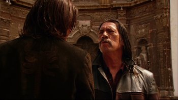 Movie still from “Once Upon a Time in Mexico” (2003), directed by Robert Rodriguez – A man with long black hair talking to another man; Medium shot, Over the shoulder angle