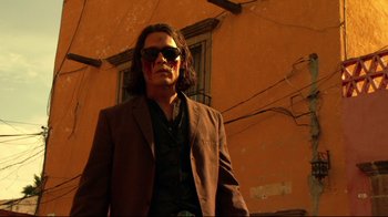 Movie still from “Once Upon a Time in Mexico” (2003), directed by Robert Rodriguez – A man wearing a suit and sunglasses standing in front of a building; Medium shot, Low angle