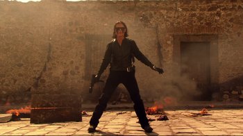 Movie still from “Once Upon a Time in Mexico” (2003), directed by Robert Rodriguez – A man in a black shirt and black gloves holding a gun; Wide shot, Low angle