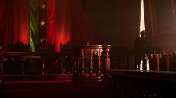 Movie still from “Once Upon a Time in Mexico” (2003), directed by Robert Rodriguez – A wooden pedestal in front of a red curtain; Wide shot, Low angle