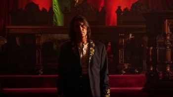 Movie still from “Once Upon a Time in Mexico” (2003), directed by Robert Rodriguez – A man in a suit standing in front of a stage; Medium shot, Low angle